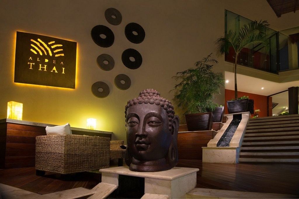 Un Buda de bronce y el letrero iluminado de Aldea Thai en el lobby